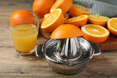 Photo of Freshly squeezed orange juice, fruits and juicer on wooden table, closeup