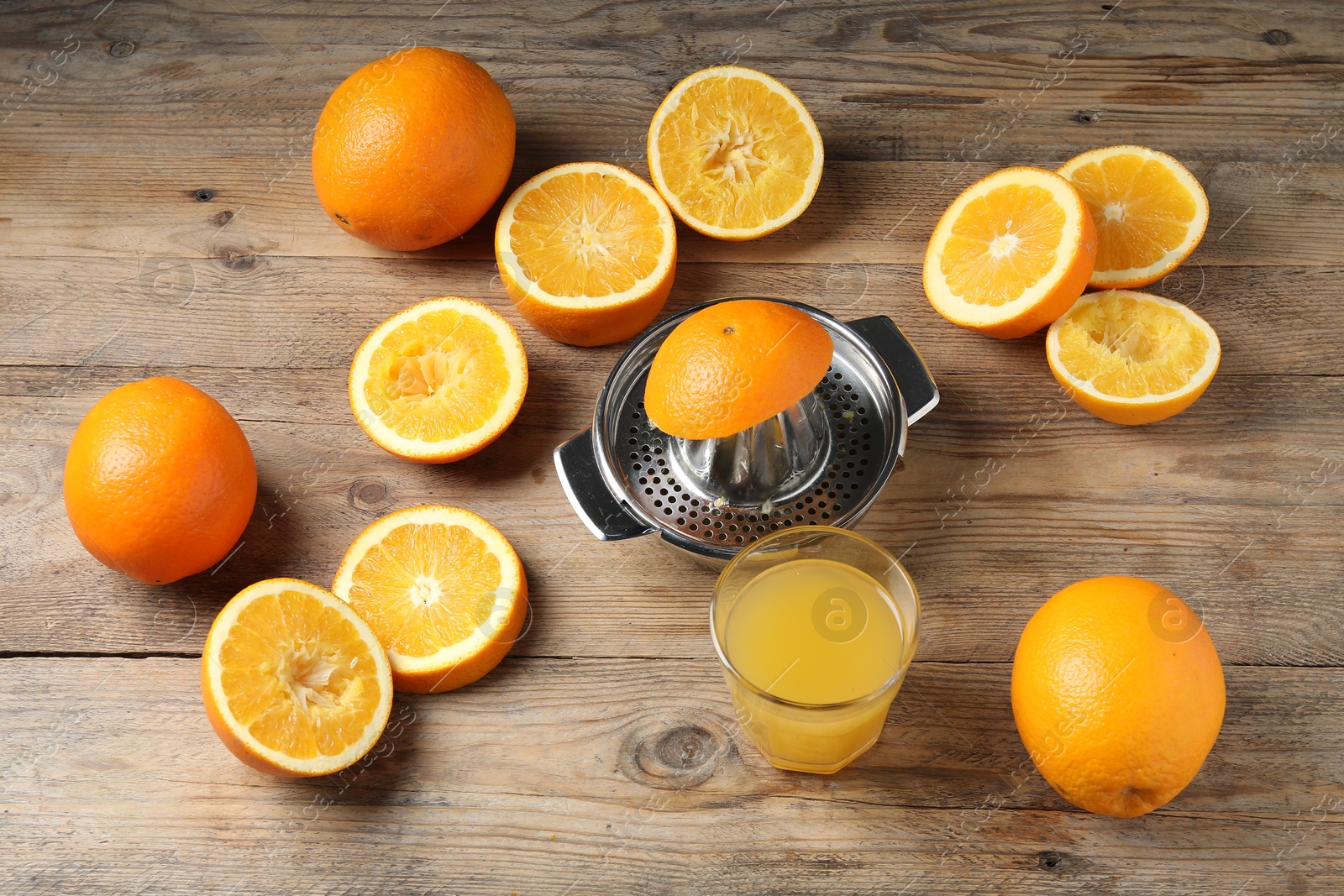 Photo of Freshly squeezed orange juice, fruits and juicer on wooden table