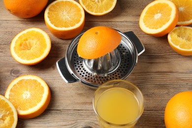 Photo of Freshly squeezed orange juice, fruits and juicer on wooden table