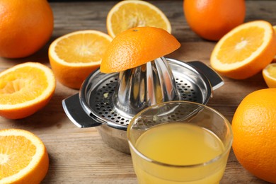 Photo of Freshly squeezed orange juice, fruits and juicer on wooden table, closeup