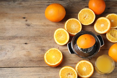 Photo of Freshly squeezed orange juice, fruits and juicer on wooden table, flat lay. Space for text
