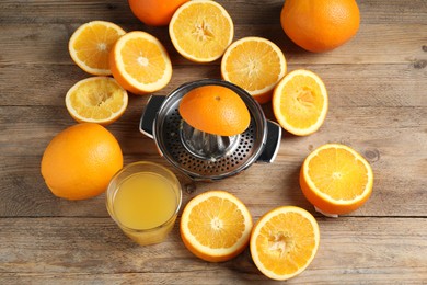 Photo of Freshly squeezed orange juice, fruits and juicer on wooden table, flat lay