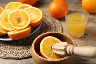 Photo of Freshly squeezed orange juice, fruits and juicer on wooden table, closeup