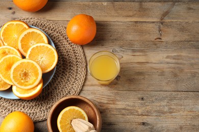 Photo of Freshly squeezed orange juice, fruits and juicer on wooden table, flat lay. Space for text