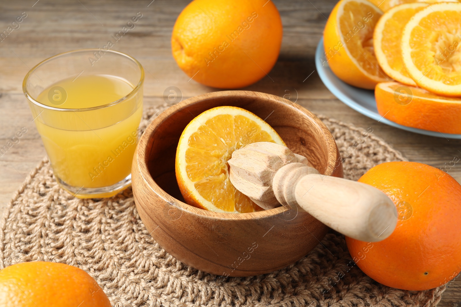 Photo of Freshly squeezed orange juice, fruits and juicer on wooden table, closeup