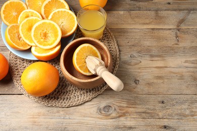 Photo of Freshly squeezed orange juice, fruits and juicer on wooden table, above view. Space for text