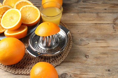 Photo of Freshly squeezed orange juice, fruits and juicer on wooden table. Space for text