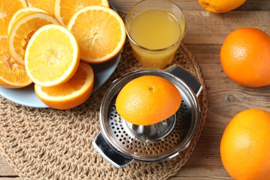 Photo of Freshly squeezed orange juice, fruits and juicer on wooden table, above view
