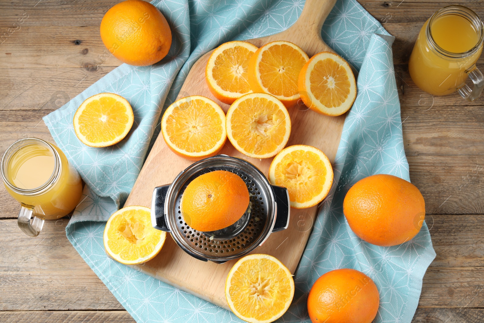 Photo of Freshly squeezed orange juice, fruits, juicer and towel on wooden table, flat lay