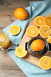 Photo of Freshly squeezed orange juice, fruits, juicer and towel on wooden table, flat lay