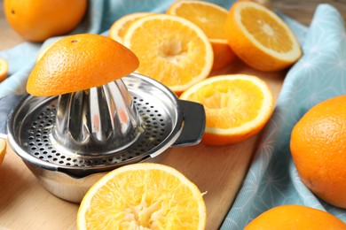 Photo of Squeezer and oranges on wooden table, closeup. Making fresh juice