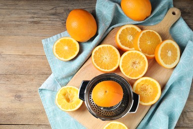 Photo of Squeezer and oranges on wooden table, flat lay. Making fresh juice