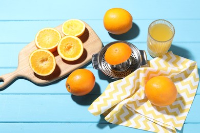 Photo of Freshly squeezed orange juice, fruits and juicer on blue wooden table, above view
