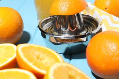 Photo of Squeezer and oranges on blue wooden table, closeup. Making fresh juice