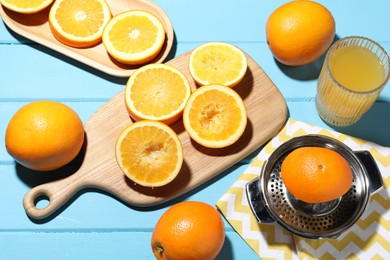 Photo of Freshly squeezed orange juice, fruits and juicer on blue wooden table, above view