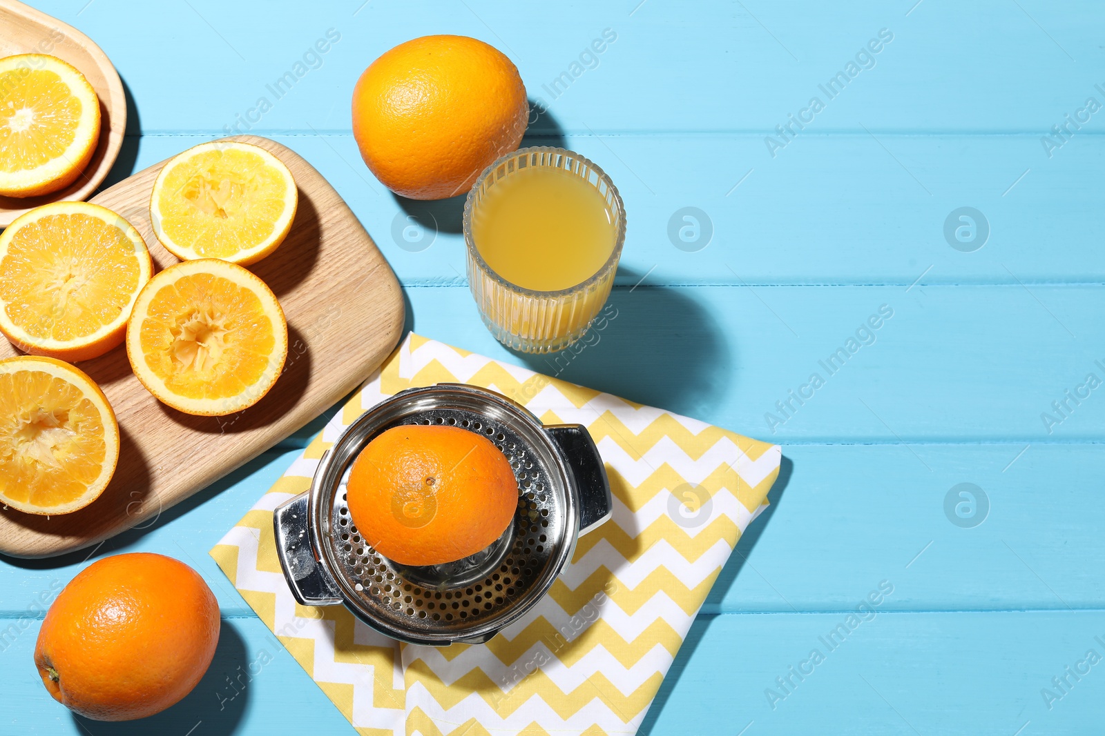 Freshly squeezed orange juice, fruits and juicer on blue wooden table, above view. Space for text Photo of Freshly squeezed orange juice, fruits and juicer on blue wooden table, above view. Space for text