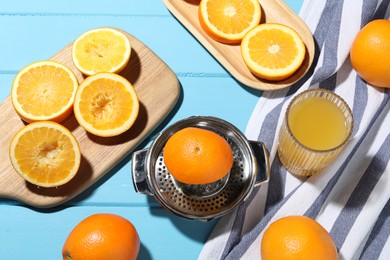 Photo of Freshly squeezed orange juice, fruits and juicer on blue wooden table, flat lay