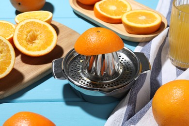 Photo of Squeezer, oranges and fresh juice on blue wooden table, closeup