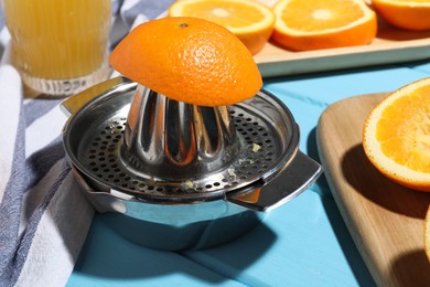 Photo of Squeezer, oranges and fresh juice on blue wooden table, closeup