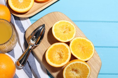 Photo of Squeezer, oranges and fresh juice on blue wooden table, flat lay