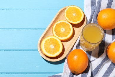 Photo of Freshly squeezed orange juice and fruits on blue wooden table, flat lay. Space for text