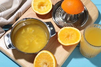 Photo of Freshly squeezed orange juice, fruits and juicer on blue wooden table, closeup