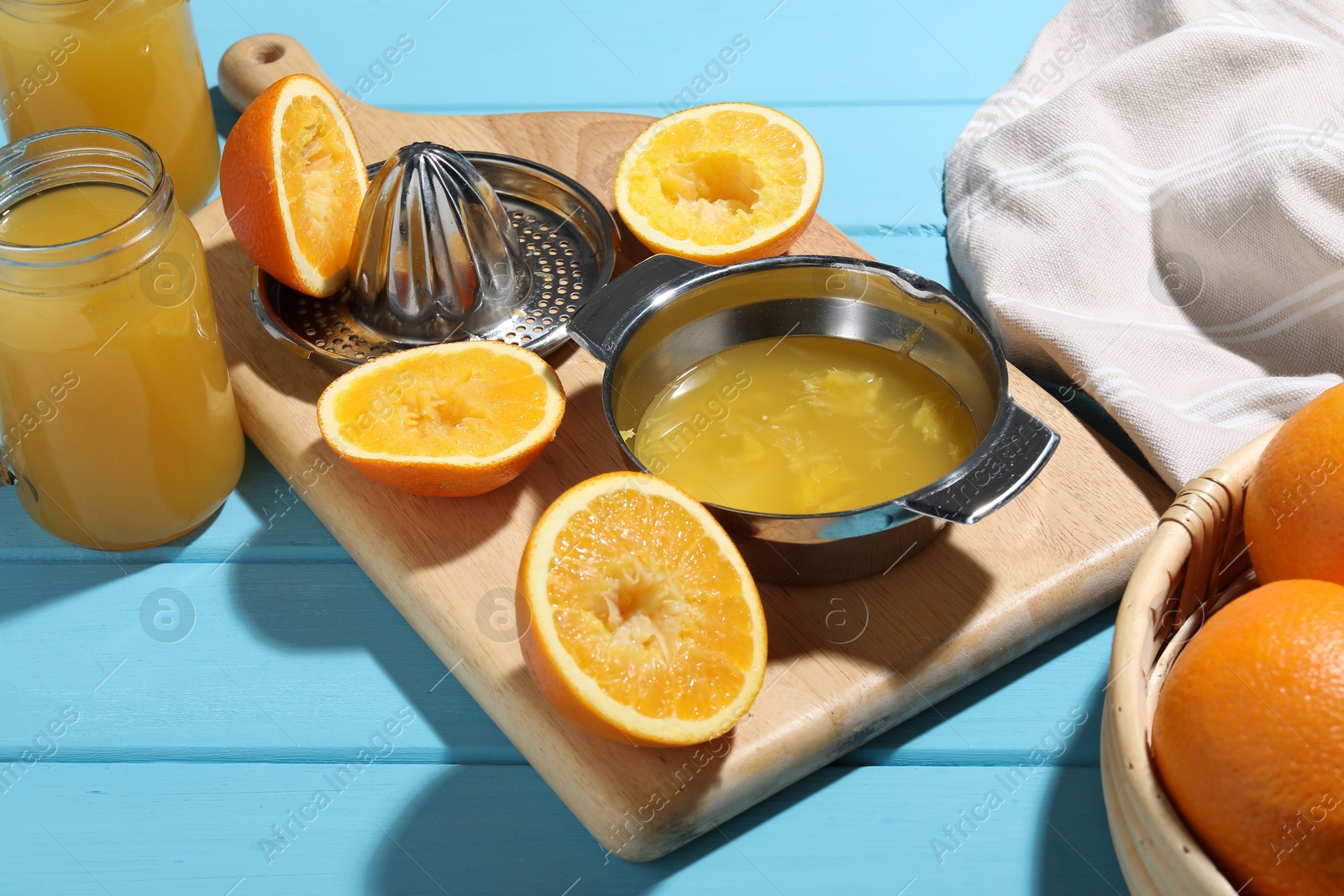 Freshly squeezed orange juice, fruits, juicer and towel on blue wooden table, closeup Photo of Freshly squeezed orange juice, fruits, juicer and towel on blue wooden table, closeup