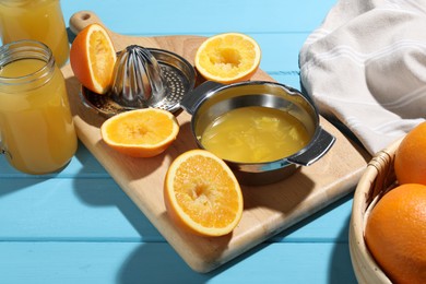 Photo of Freshly squeezed orange juice, fruits, juicer and towel on blue wooden table, closeup