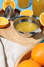 Photo of Freshly squeezed orange juice, fruits, juicer and towel on table, closeup