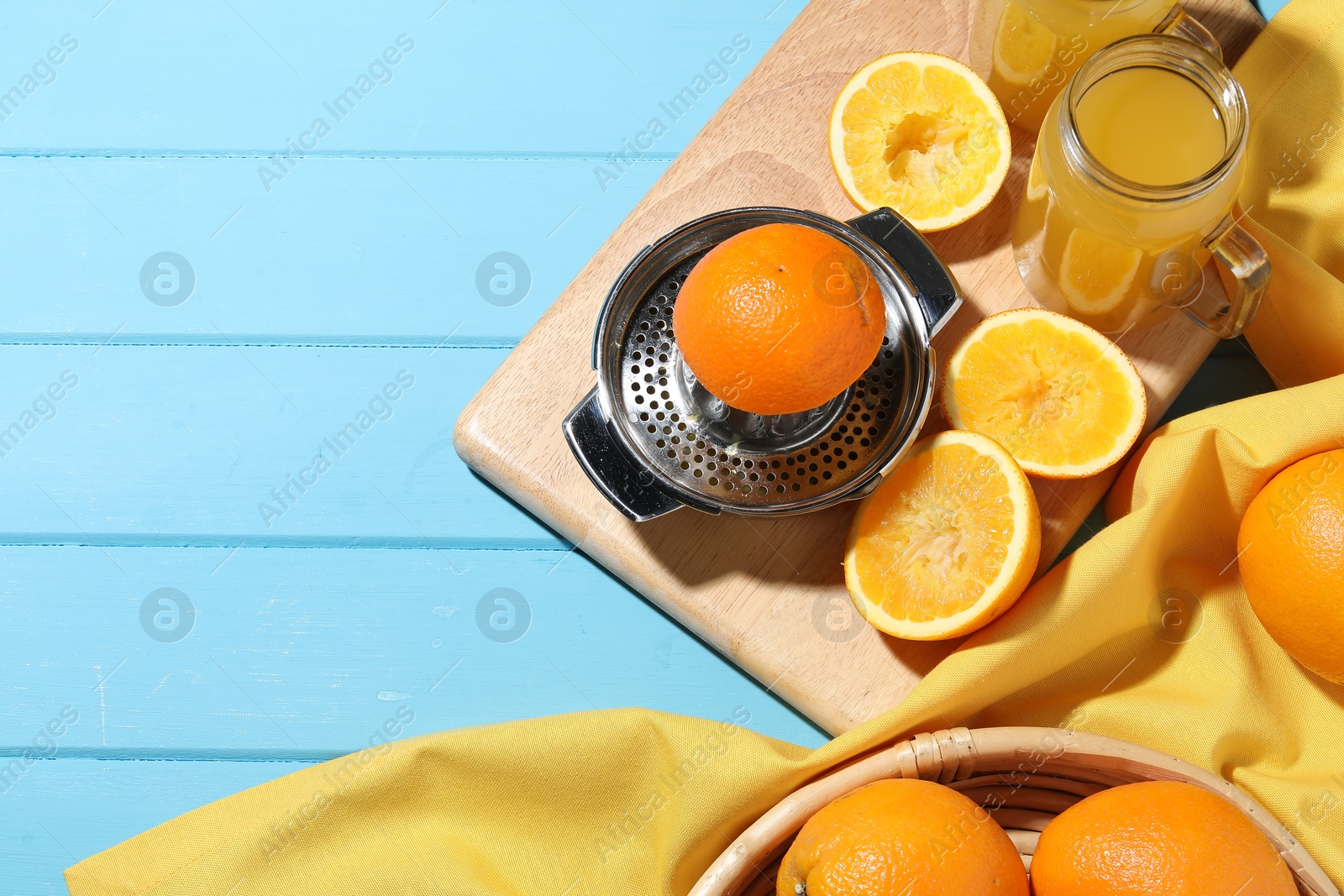 Freshly squeezed orange juice, fruits, juicer and towel on blue wooden table, flat lay. Space for text Photo of Freshly squeezed orange juice, fruits, juicer and towel on blue wooden table, flat lay. Space for text
