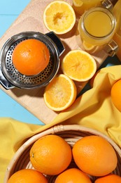 Photo of Freshly squeezed orange juice, fruits, juicer and towel on blue wooden table, flat lay