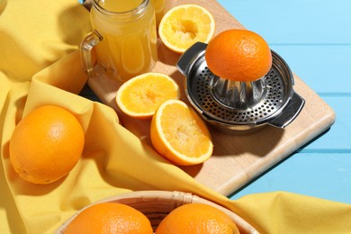 Photo of Squeezer, oranges and fresh juice on blue wooden table, closeup