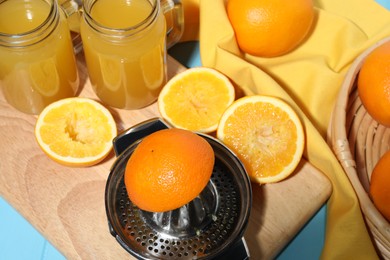 Photo of Squeezer, oranges and fresh juice on blue wooden table, closeup