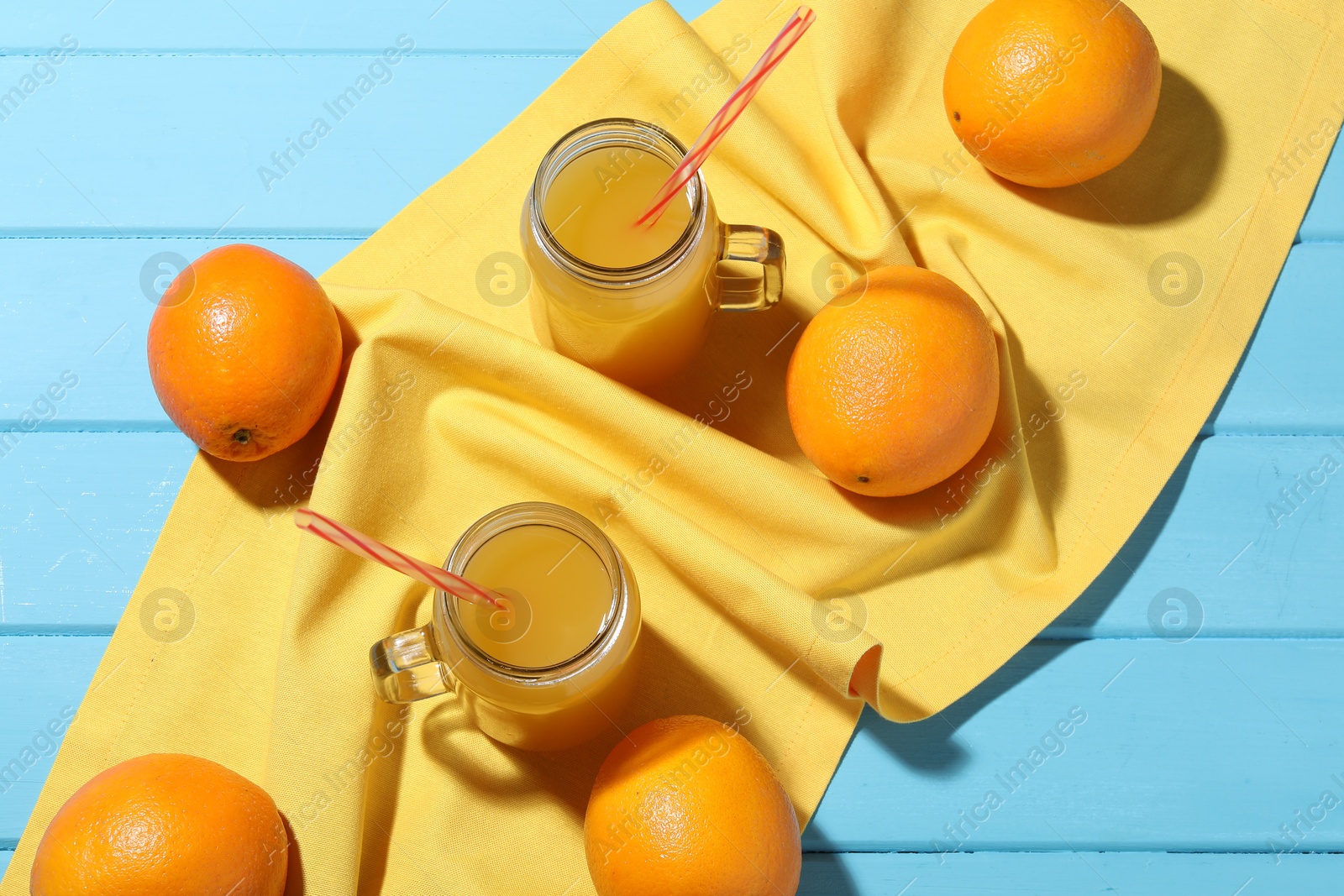 Freshly squeezed orange juice, fruits and towel on blue wooden table, flat lay Photo of Freshly squeezed orange juice, fruits and towel on blue wooden table, flat lay