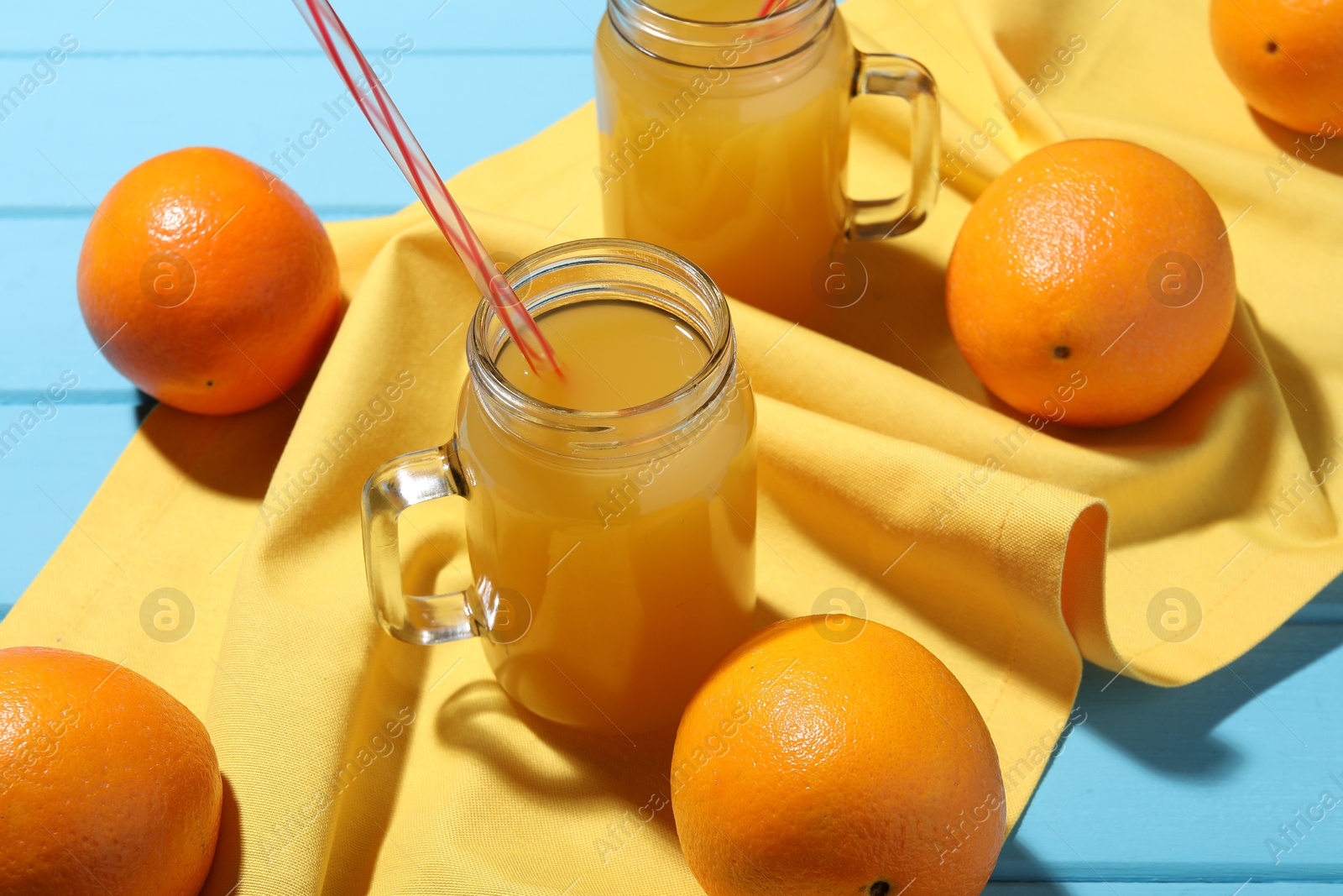 Freshly squeezed orange juice, fruits and towel on blue wooden table, closeup Photo of Freshly squeezed orange juice, fruits and towel on blue wooden table, closeup