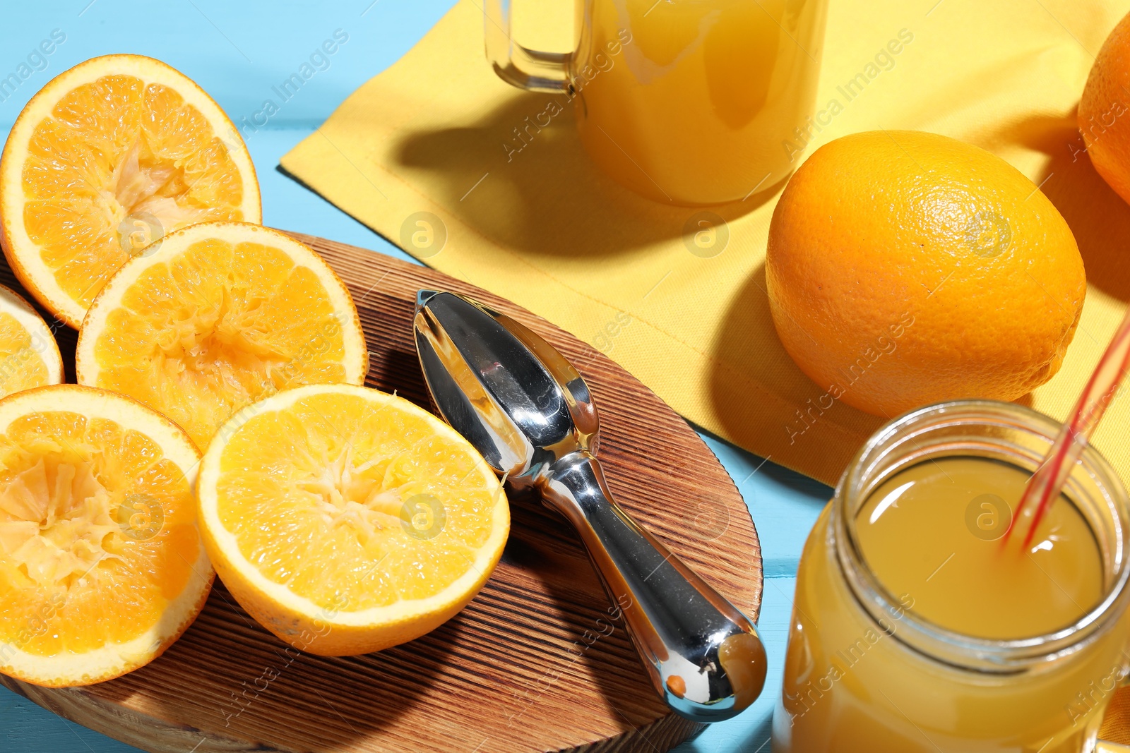 Freshly squeezed orange juice, fruits and juicer on blue wooden table, closeup Photo of Freshly squeezed orange juice, fruits and juicer on blue wooden table, closeup