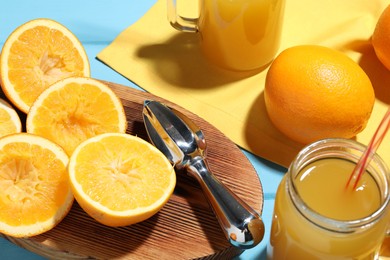 Photo of Freshly squeezed orange juice, fruits and juicer on blue wooden table, closeup
