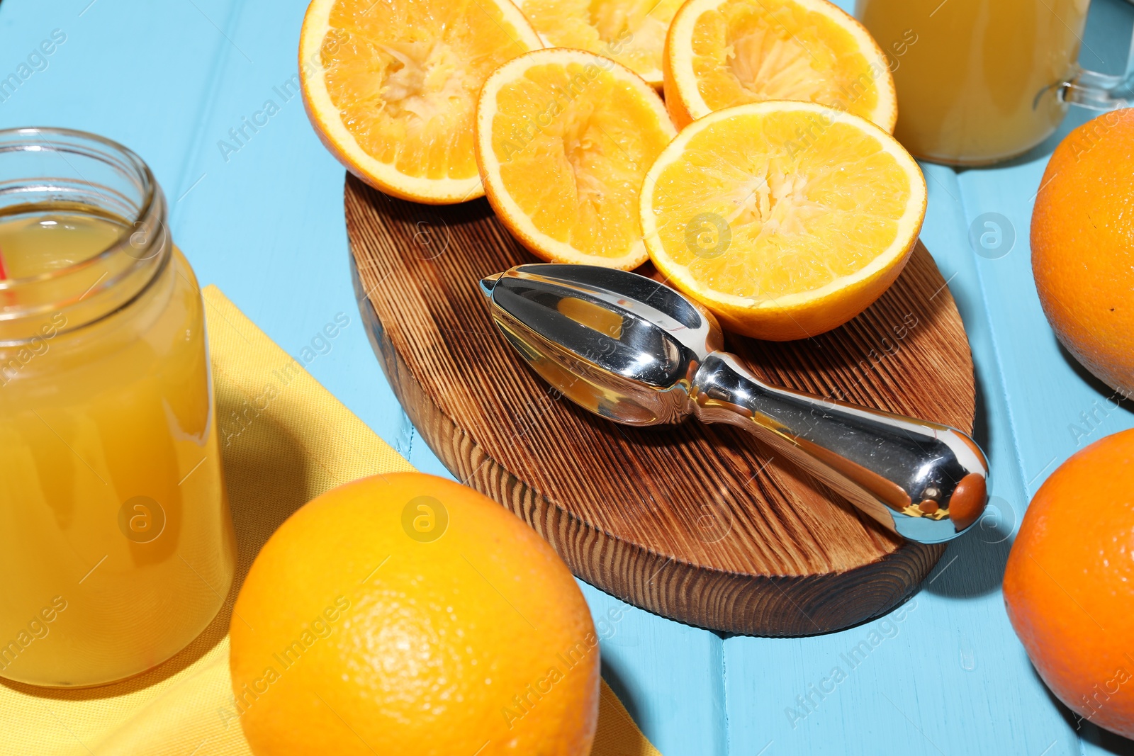 Freshly squeezed orange juice, fruits and juicer on blue wooden table, closeup Photo of Freshly squeezed orange juice, fruits and juicer on blue wooden table, closeup