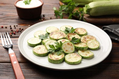 Photo of Delicious fried courgette slices with parsley served on wooden table, closeup
