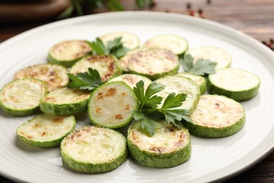 Photo of Delicious fried courgette slices with parsley on table, closeup