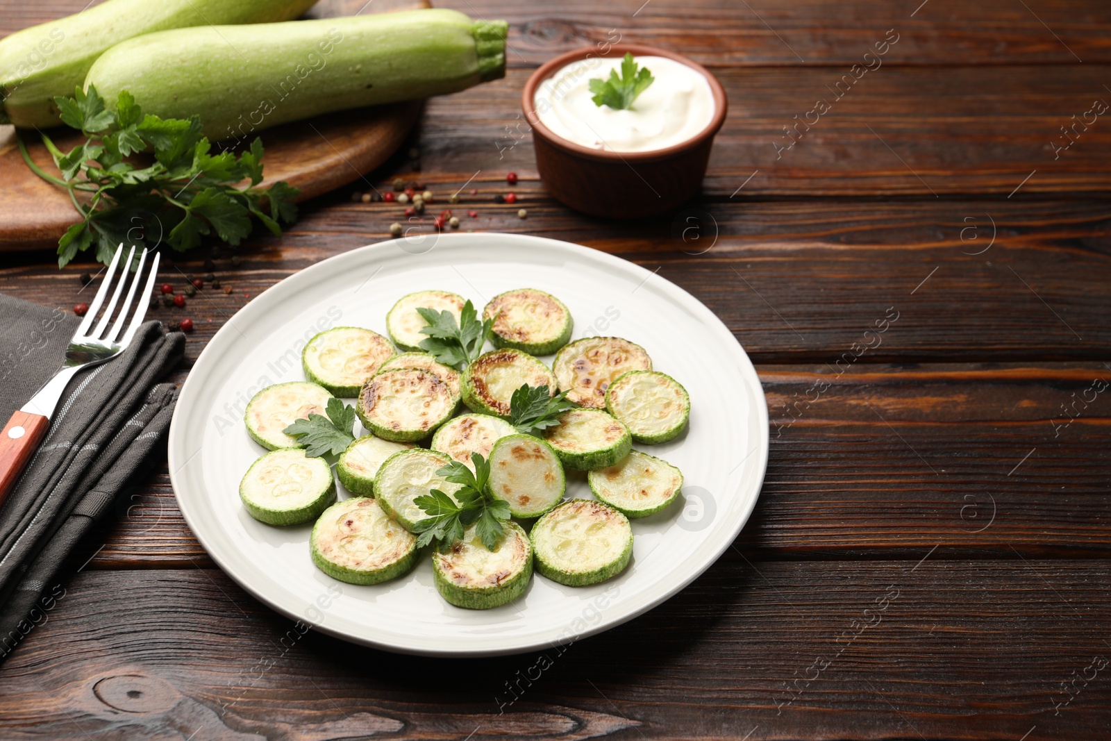 Delicious fried courgette slices with parsley served on wooden table Photo of Delicious fried courgette slices with parsley served on wooden table