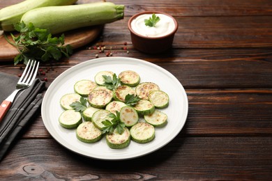 Photo of Delicious fried courgette slices with parsley served on wooden table