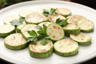Photo of Delicious fried courgette slices with parsley on plate, closeup