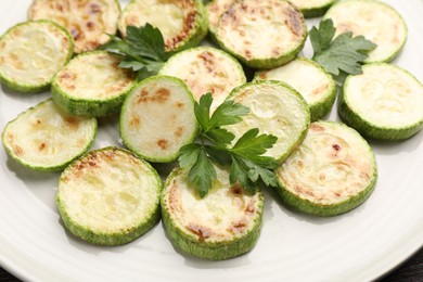 Photo of Delicious fried courgette slices with parsley on plate, closeup
