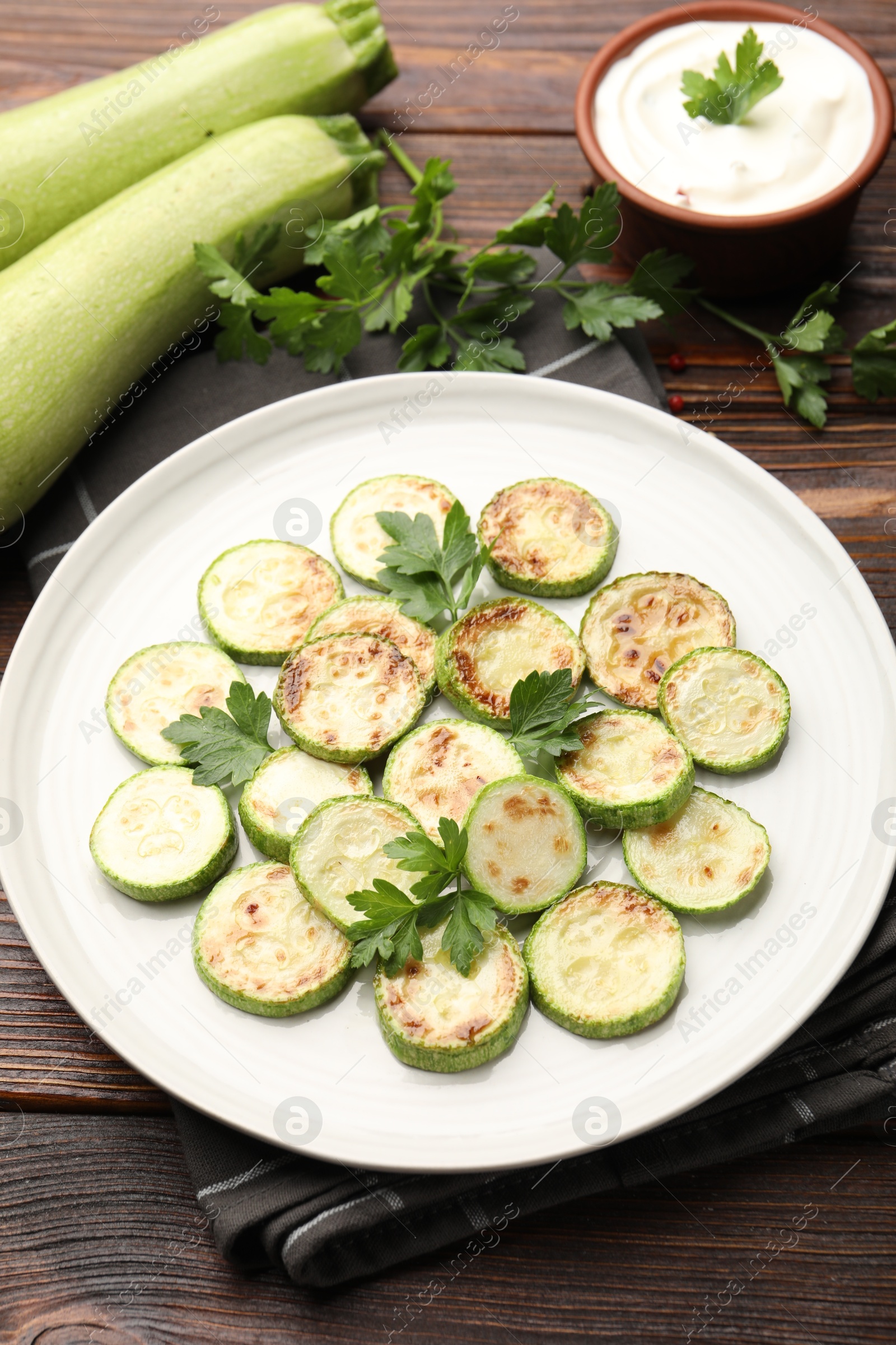 Delicious fried courgette slices with parsley served on wooden table, closeup Photo of Delicious fried courgette slices with parsley served on wooden table, closeup