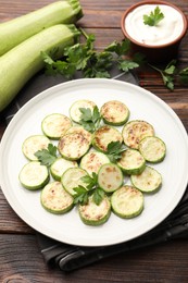 Photo of Delicious fried courgette slices with parsley served on wooden table, closeup