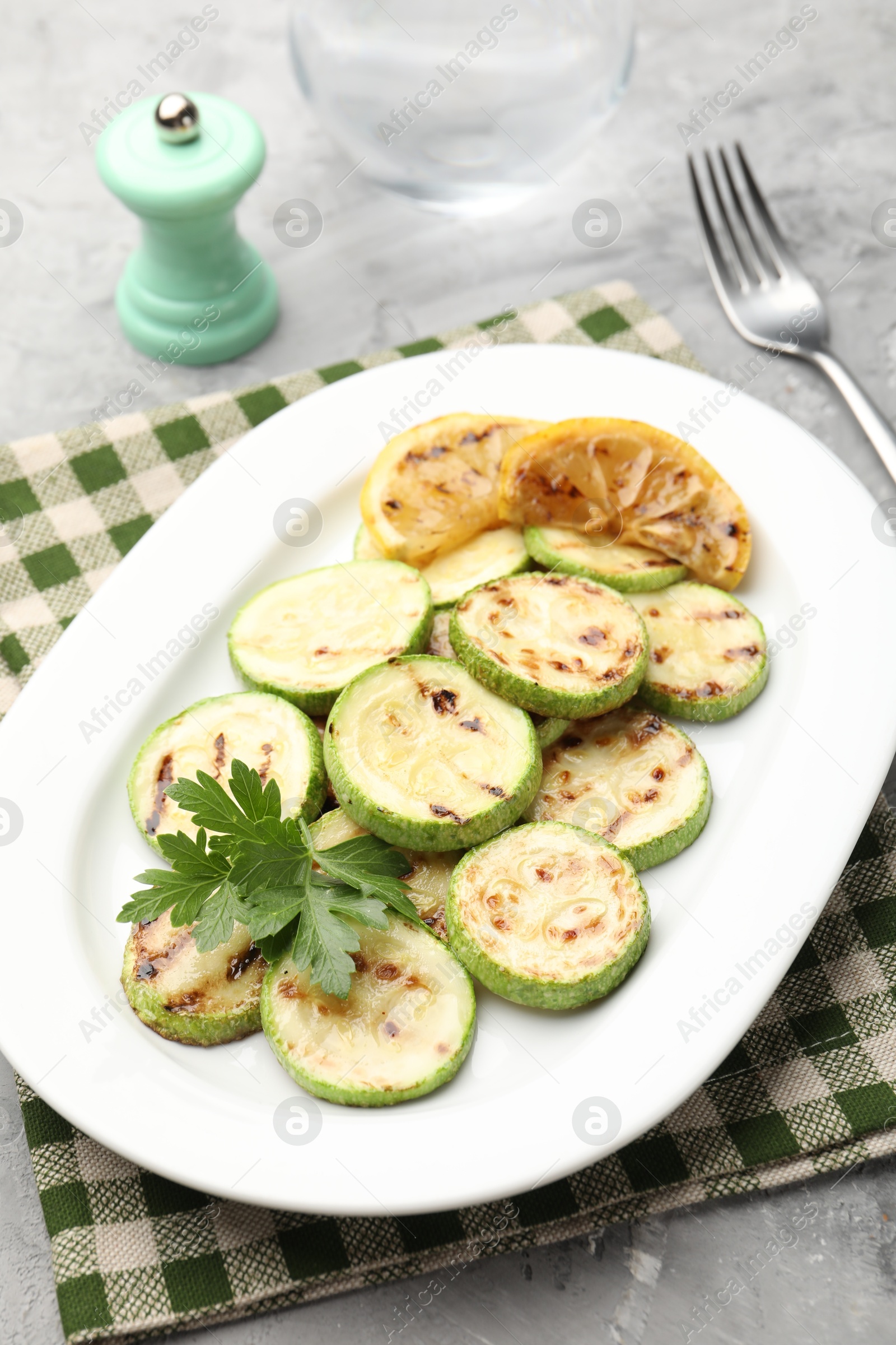 Delicious fried courgette slices with lemon and parsley served on grey table, closeup Photo of Delicious fried courgette slices with lemon and parsley served on grey table, closeup