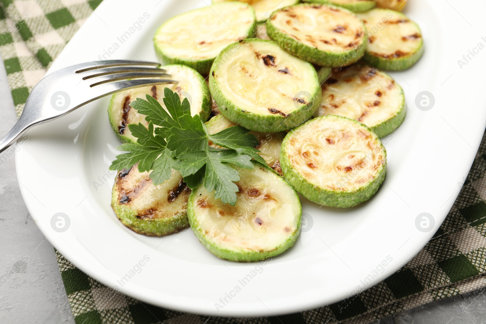 Delicious fried courgette slices with parsley on grey table, closeup Photo of Delicious fried courgette slices with parsley on grey table, closeup