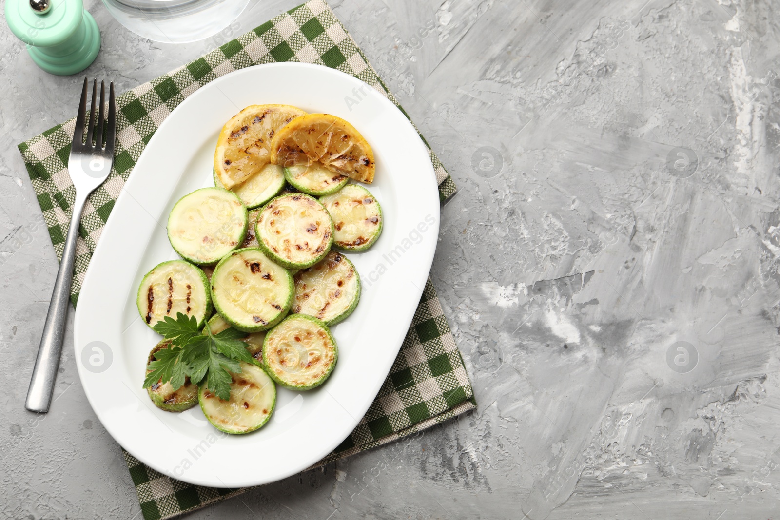 Delicious fried courgette slices with lemon and parsley served on grey table, flat lay. Space for text Photo of Delicious fried courgette slices with lemon and parsley served on grey table, flat lay. Space for text