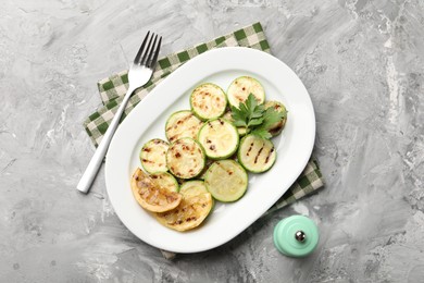 Photo of Delicious fried courgette slices with lemon and parsley served on grey table, flat lay